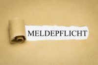 Foto: Aufgerissenes Papier mit Aufschrift Meldepflicht